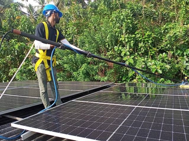 Technician harnessed and cleaning a rooftop array in Galle